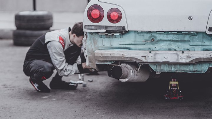 A mechanic working on a jacked up car
