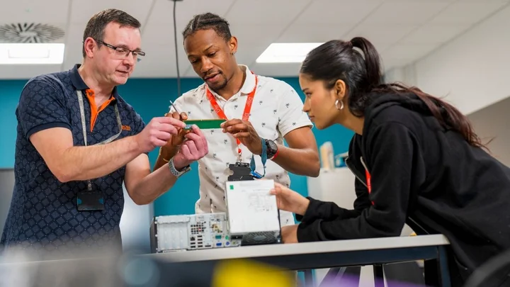People working together to examine electronic components and equipment during a hands‑on classroom learning activity.