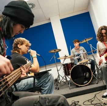 Music students rehearsing as a band at The Manchester College, using guitars, drums and professional performance equipment.