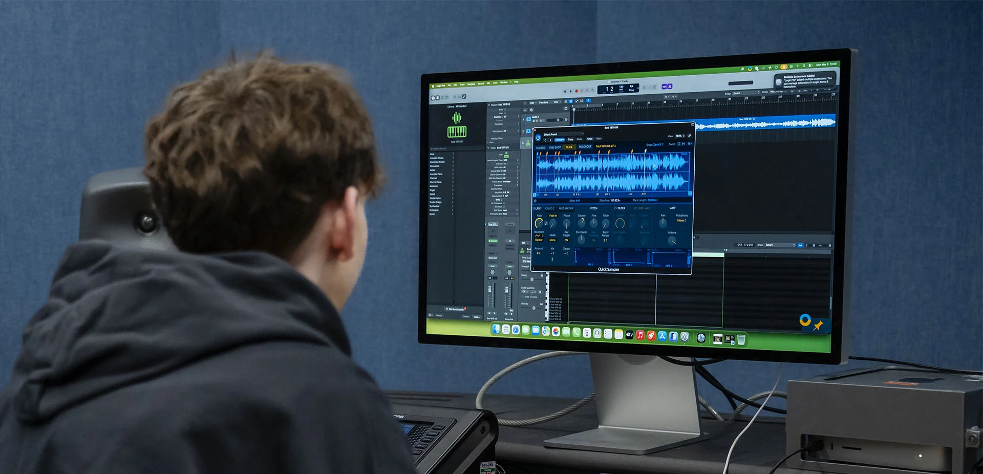 People working together at a music production workstation, using audio editing software, a keyboard controller and studio equipment during a practical learning session.