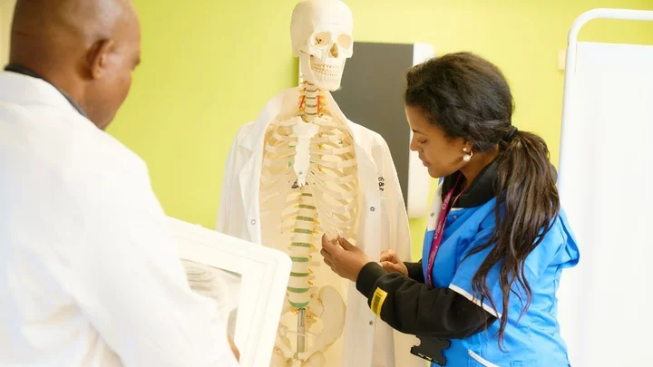Health and social care learners examining a skeleton model during an anatomy and physiology training session.