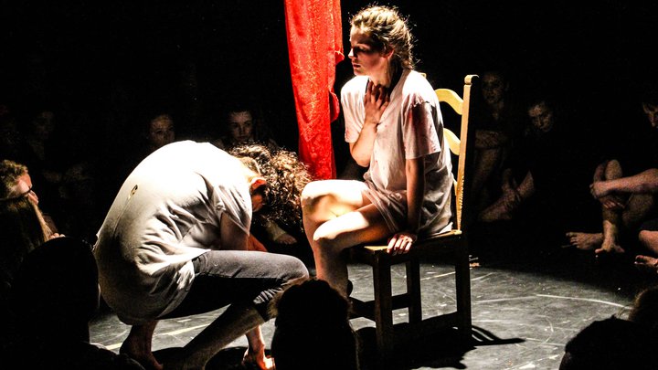 A female student sat down facing a male student while they perform on stage